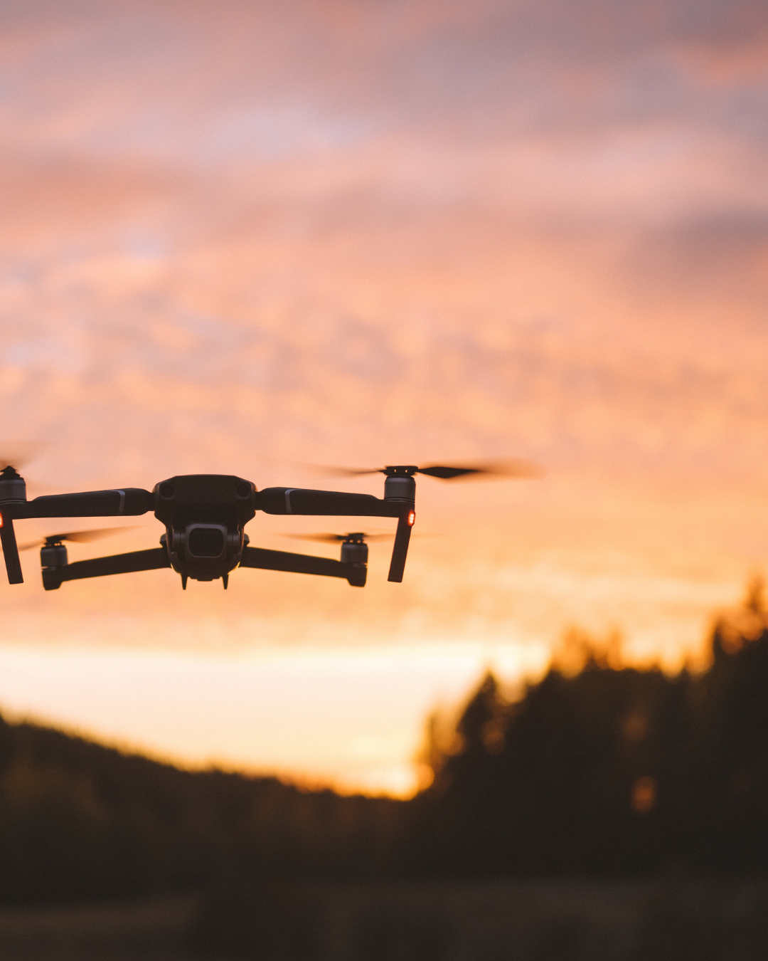 Dron de seguridad volando al atardecer sobre una zona rural o forestal